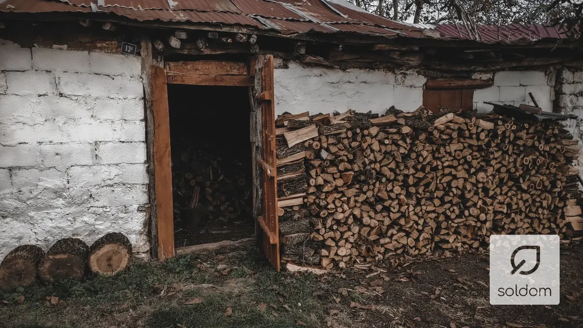 Drewutnia przy domu z ułożonym, sezonowanym drewnem opałowym